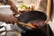 Man stirring onion slices in frying pan