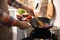 Man stirring onion slices in frying pan, closeup