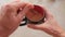 A man stirs with a spoon in a cup of coffee with milk, top view.