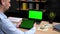 Man stock trader broker looks tablet with green display, laptop green screen