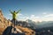 Man on the stone with raised up arms against mountain valley