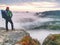 Man stopped for moment walking in foggy rocks. View over mist