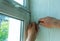 A man straightens a plastic window or door with a screwdriver and a special mallet.