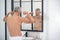 Man straining muscles of arms looking in mirror