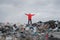 Man with stretched arms standing on landfill, environmental concept.