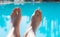 Man stretched legs at swimming pool with clear turquoise water