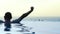 Man stretches in infinity pool looks at beach view