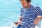 Man in striped sailor shirt using mobile phone at sea