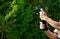 Man in a striped T-shirt opens a bottle of sparkling wine in the garden during a family celebration. he pushes the stopper of the