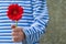 A man in a striped T-shirt with a red gerbera. Women`s day concept. A man with a red flower. Be my Valentine. Blurred background