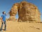 A man stroking the rock formation known as the Elephant Rock in Al Ula, Saudi Arabi KSA