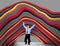 A man struggles to hold up the weight of long curving tubes of various colors