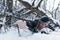 A man struggling for his life under a fallen tree in a deep snow