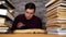 Man student boring reading book at library with a lot of books in university.