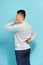 Man student feel shoulder pain with blue background, asian