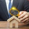 A man is studying a house through a magnifying glass. Fair value of real estate. Property valuation. Legal deal. Standards and