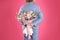 Man in stylish suit hiding beautiful flower bouquet behind his back on pink background