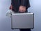 Man in suit carries metal briefcase with dollars