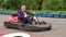 Man in a suit driving Go-Kart car in a playground.