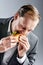 Man in suit eats BLT eagerly