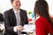 Man in suit holds out signature document to woman