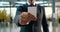 a man in a suit holds a white paper mockup in front of him