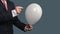 Man in Suit lets a Balloon burst with a needle