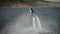 A man in a suit performs tricks on a flyboard. Extreme activity on the water.