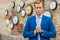 Man in suit standing near wall with clocks