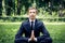 Man in a suit with tie. Business man relaxing in a park in the lotus position, he can`t relax in any way, meditation in the park.