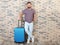 Man with suitcase near brick wall