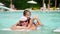 Man in sun glasses, father and daughter, kid girl, playing in the pool water, having fun together. Happy family relaxing