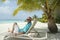 Man on a sun lounger under the palm tree in the Maldivian beach