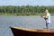 A man in sunglasses on a boat is fishing with the help of spinning in beautiful weather on the lake, active recreation