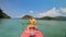 Man with sunglasses and hat rows pink plastic canoe along sea ag