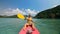 Man with sunglasses and hat rows pink plastic canoe along sea ag