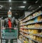 A man in a supermarket pushes a cart between the shelves