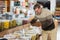 Man in supermarket scooping marinated green olives into plastic bag