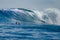 Man on a surfboard paddles to a big wave