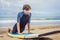 Man surfer on the beach warming up before surfing, Surf Man in a wet suit with a surfboard on the ocean,