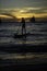 Man surfs on ocean near beach at sunset