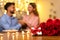 Man surprises partner with gift and roses during romantic candlelit dinner