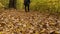 A man in sweatpants and a sweatshirt with a bag on his shoulder walks down the fallen yellow leaves in an autumn forest