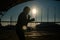 A man in a sweatshirt trains in boxing at the stadium at sunset. Athlete silhouette.