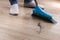 The man sweeps the debris into a blue scoop with brush