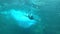 Man swimming under tuquoise blue water of a waterfall stream. Underwater view.