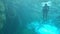 A man swimming underwater beneath the waterfall crystal clear blue water.