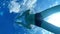 A man swims in the pool. View from the bottom of the pool on an athlete swimming. Reflection of the sky and bubbles in