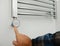 Man switch on electric towel rail radiator. Towel Radiator Heating Elements. Thermostatic Electric Towel Rail in Bathroom