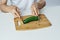 Man at the table on a white isolated background cuts a cucumber on a cutting board, vegetarianism, diet